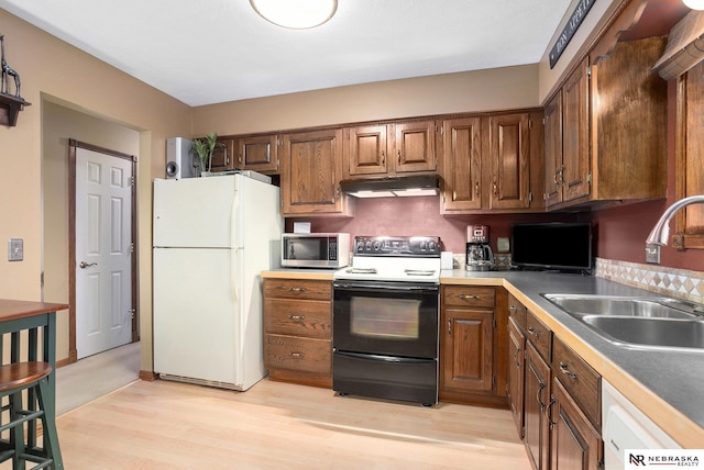 2219 Independence Dr, Lincoln, NE 68521 - kitchen with freestanding refrigerator, black range with electric cooktop, stainless steel microwave, light wood-style flooring, and under cabinet range hood