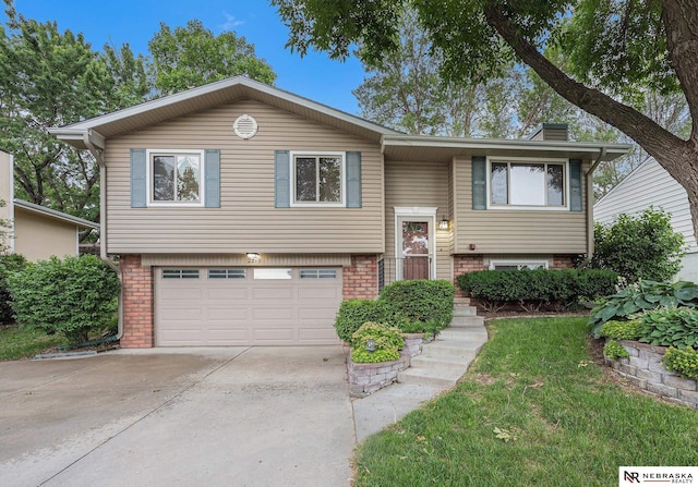 2219 Independence Dr, Lincoln, NE 68521 - split foyer home with a garage, concrete driveway, brick siding, and a chimney