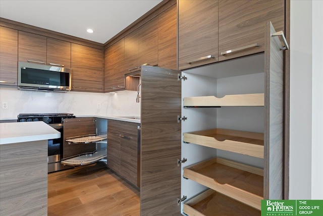 200 S 31st Ave Unit 4209, Omaha, NE 68131 - kitchen featuring stainless steel microwave, range, brown cabinetry, wood finished floors, and modern cabinets