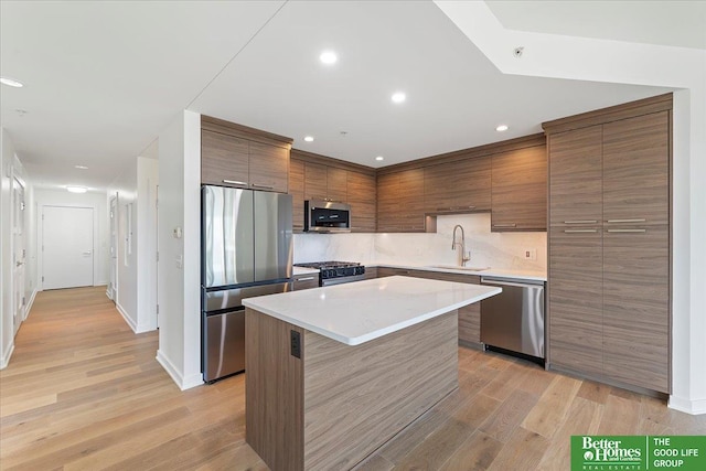 200 S 31st Ave Unit 4209, Omaha, NE 68131 - kitchen featuring appliances with stainless steel finishes, a kitchen island, light wood-type flooring, decorative backsplash, and light countertops