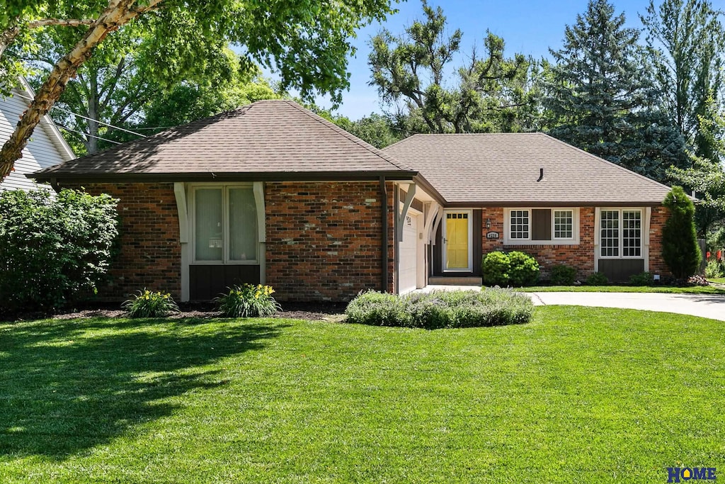 4220 S 30th St, Lincoln, NE 68502 - view of front of property with brick siding, a shingled roof, a front yard, and concrete driveway
