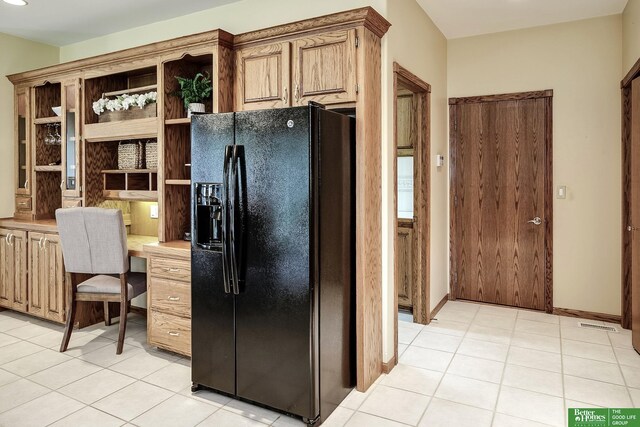 16140 Josephine St, Omaha, NE 68136 - kitchen with black fridge, open shelves, built in desk, light tile patterned flooring, and light countertops