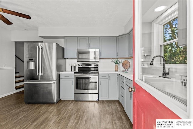 301 Gladys Ave, Yutan, NE 68073 - kitchen with appliances with stainless steel finishes, gray cabinetry, ceiling fan, wood finished floors, and light countertops
