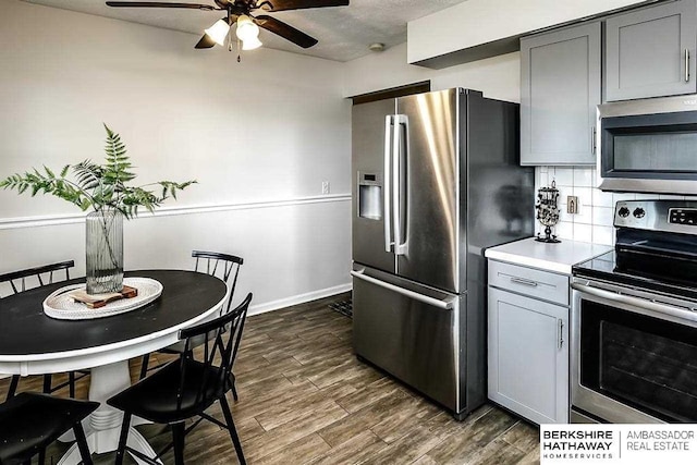 301 Gladys Ave, Yutan, NE 68073 - kitchen featuring appliances with stainless steel finishes, a ceiling fan, gray cabinetry, dark wood-style floors, and light countertops