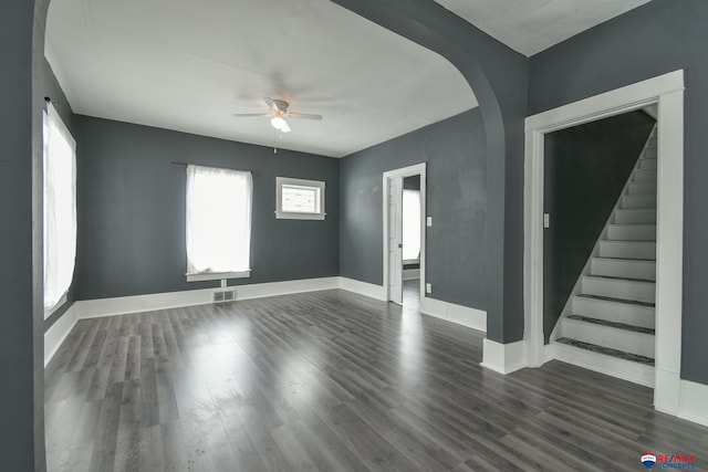 603 E Maple St, Sutton, NE 68979 - unfurnished living room featuring a ceiling fan, dark wood-style floors, arched walkways, and stairs