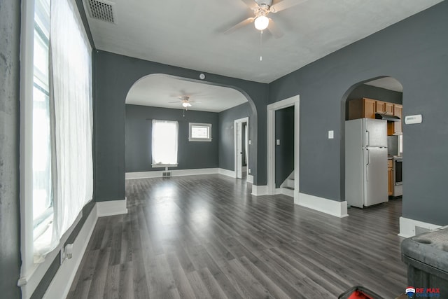 603 E Maple St, Sutton, NE 68979 - unfurnished living room featuring a ceiling fan, arched walkways, dark wood-style floors, and stairs
