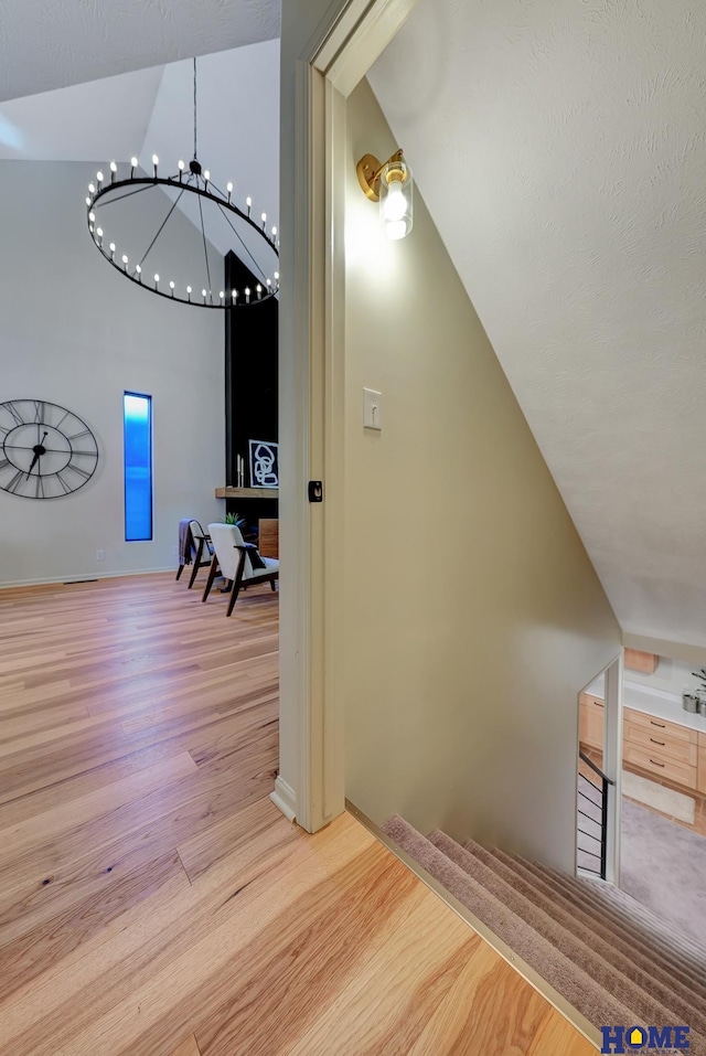 6833 Summerset Ct, Lincoln, NE 68516 - hall featuring wood finished floors, a chandelier, high vaulted ceiling, and stairway