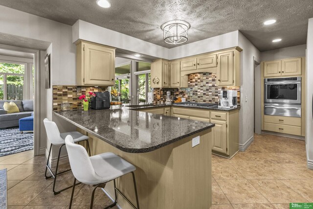 1015 N 127th Cir, Omaha, NE 68154 - kitchen featuring appliances with stainless steel finishes, a warming drawer, a kitchen bar, decorative backsplash, and a peninsula