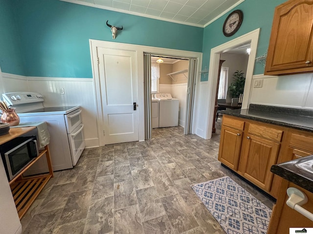 624 A St, Lincoln, NE 68502 - kitchen with washer and clothes dryer, stainless steel microwave, range with two ovens, wainscoting, and dark countertops
