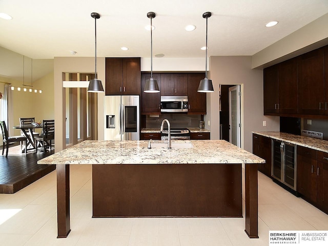 6535 N 157th St, Omaha, NE 68116 - kitchen featuring wine cooler, stainless steel appliances, dark brown cabinets, light stone countertops, and a center island with sink