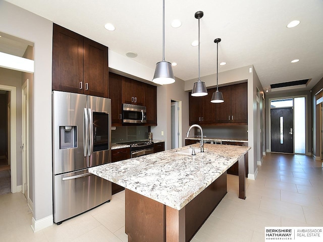 6535 N 157th St, Omaha, NE 68116 - kitchen featuring appliances with stainless steel finishes, recessed lighting, dark brown cabinetry, light stone countertops, and a kitchen island with sink