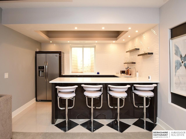 6535 N 157th St, Omaha, NE 68116 - kitchen with stainless steel fridge, a tray ceiling, a peninsula, light countertops, and recessed lighting