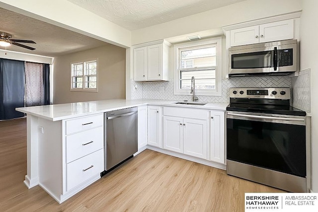 7025 S 41st St, Bellevue, NE 68147 - kitchen featuring appliances with stainless steel finishes, a peninsula, light wood finished floors, tasteful backsplash, and a textured ceiling