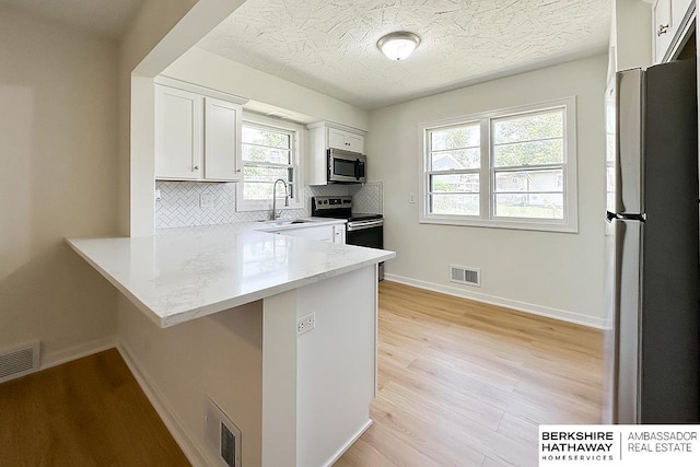 7025 S 41st St, Bellevue, NE 68147 - kitchen featuring stainless steel appliances, decorative backsplash, light wood finished floors, white cabinets, and a textured ceiling