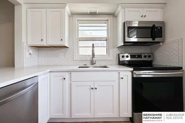 7025 S 41st St, Bellevue, NE 68147 - kitchen featuring appliances with stainless steel finishes, decorative backsplash, and white cabinetry