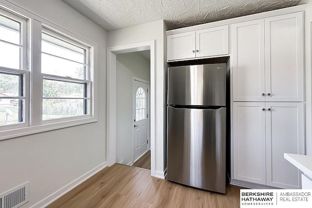 7025 S 41st St, Bellevue, NE 68147 - kitchen featuring freestanding refrigerator, light wood-style floors, white cabinets, and plenty of natural light