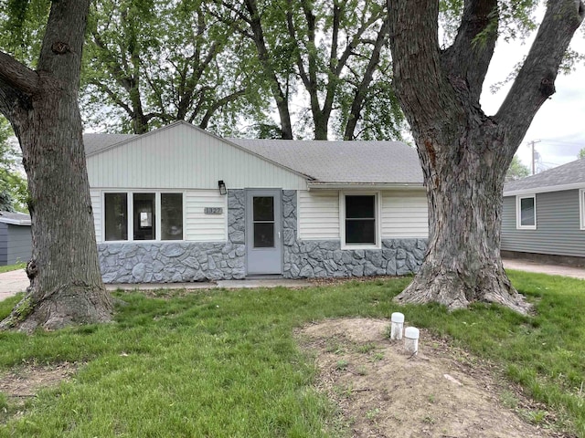 1327 N Cedar Ave, Hastings, NE 68901 - ranch-style house featuring stone siding, roof with shingles, and a front yard