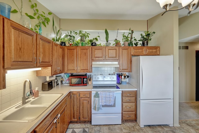 8032 E Avon Ln, Lincoln, NE 68505 - kitchen with white appliances, under cabinet range hood, decorative backsplash, light countertops, and brown cabinets