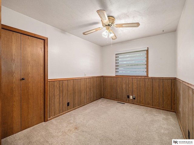 9418 Meredith Ave, Omaha, NE 68134 - spare room featuring wainscoting, wooden walls, a ceiling fan, and carpet