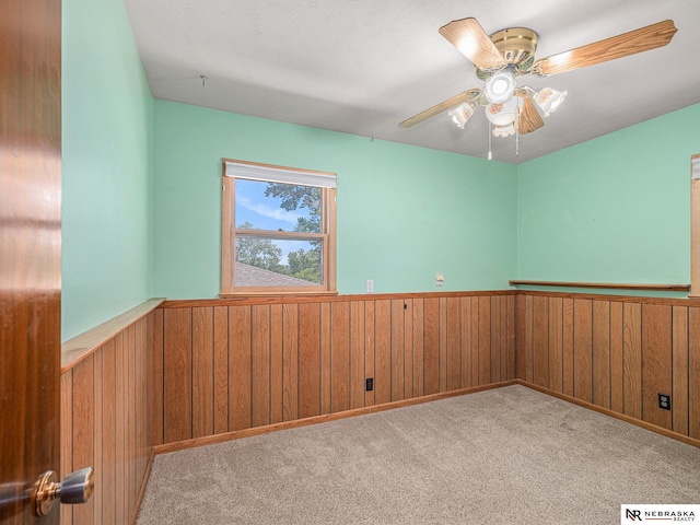 9418 Meredith Ave, Omaha, NE 68134 - carpeted empty room featuring wainscoting, wooden walls, and a ceiling fan