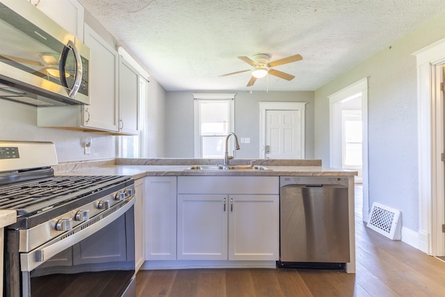 6316 Spencer St, Omaha, NE 68104 - kitchen featuring stainless steel appliances, a peninsula, ceiling fan, white cabinetry, and dark wood finished floors