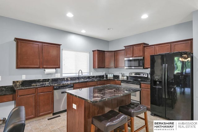 14210 Potter Pkwy, Omaha, NE 68142 - kitchen featuring appliances with stainless steel finishes, a kitchen bar, a center island, dark stone countertops, and recessed lighting