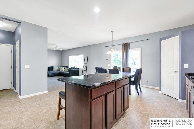 14210 Potter Pkwy, Omaha, NE 68142 - kitchen featuring a chandelier, dark stone counters, decorative light fixtures, a kitchen bar, and a ceiling fan