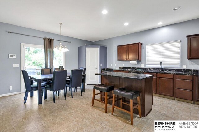 14210 Potter Pkwy, Omaha, NE 68142 - kitchen with a chandelier, a kitchen island, recessed lighting, dark stone countertops, and a kitchen bar