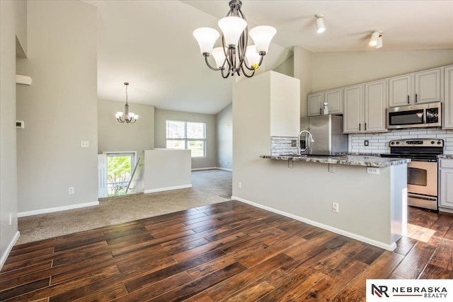 6961 N 89th Ave, Omaha, NE 68122 - kitchen with appliances with stainless steel finishes, a chandelier, dark wood-style floors, light stone countertops, and tasteful backsplash