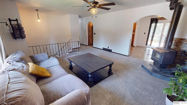 10912 V St, Omaha, NE 68137 - carpeted living room featuring arched walkways, ceiling fan, a wood stove, and a textured ceiling