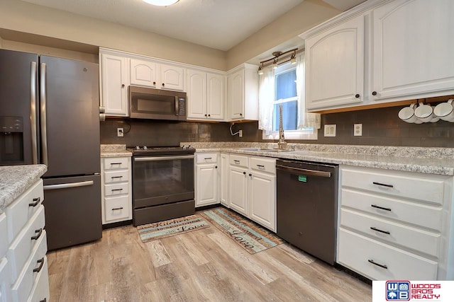 5951 Oakridge Dr, Lincoln, NE 68516 - kitchen with stainless steel appliances, white cabinets, light wood-type flooring, and decorative backsplash