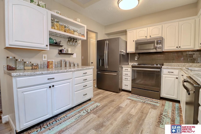 5951 Oakridge Dr, Lincoln, NE 68516 - kitchen with stainless steel appliances, light wood-style flooring, white cabinets, backsplash, and open shelves
