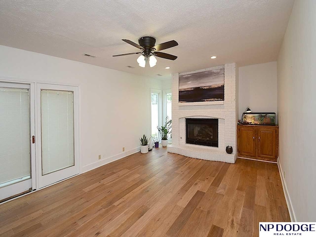 724 N 155th Ave, Omaha, NE 68154 - unfurnished living room with light wood-style floors, a fireplace, a ceiling fan, recessed lighting, and a textured ceiling