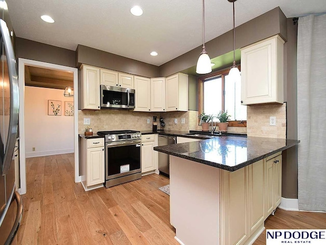 724 N 155th Ave, Omaha, NE 68154 - kitchen featuring stainless steel appliances, a peninsula, light wood finished floors, decorative light fixtures, and recessed lighting