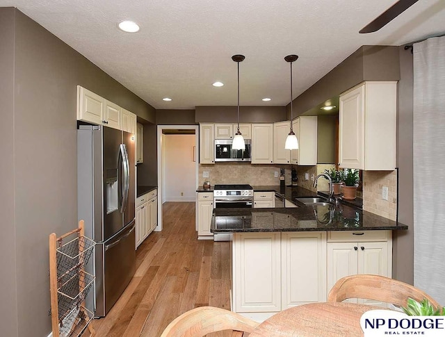724 N 155th Ave, Omaha, NE 68154 - kitchen featuring stainless steel appliances, a peninsula, light wood-style flooring, backsplash, and pendant lighting