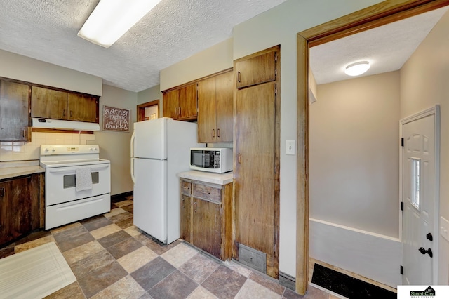 4415 S St, Lincoln, NE 68506 - kitchen featuring white appliances, under cabinet range hood, tasteful backsplash, light countertops, and a textured ceiling