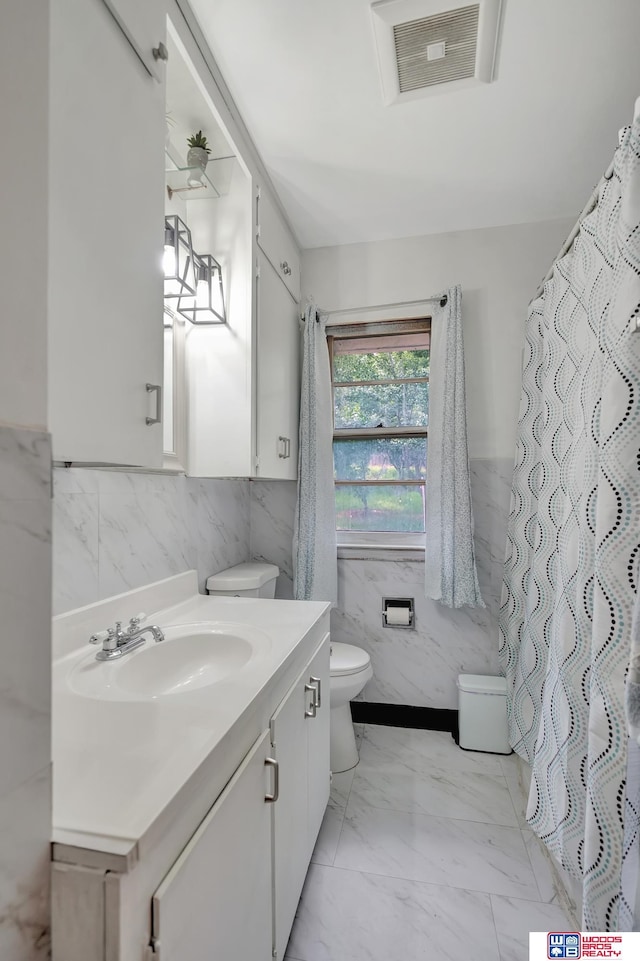6336 N 37th St, Omaha, NE 68111 - bathroom featuring tile walls, vanity, marble look tiles, and a wainscoted wall