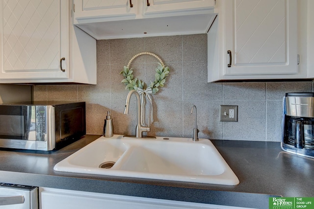 11122 Jefferson St, Omaha, NE 68137 - kitchen view of stainless steel microwave, white cabinetry, tasteful backsplash, and ventilation hood
