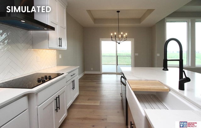 941 N 104th St, Lincoln, NE 68527 - kitchen featuring exhaust hood, black electric stovetop, a tray ceiling, a chandelier, and backsplash