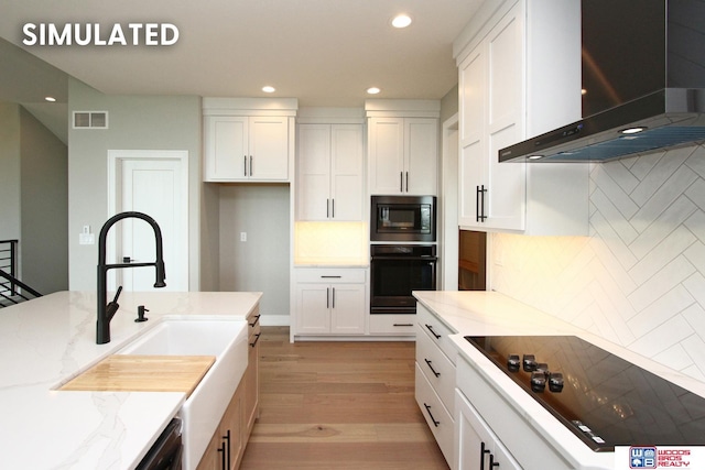 941 N 104th St, Lincoln, NE 68527 - kitchen featuring black appliances, wall chimney exhaust hood, recessed lighting, light wood-style flooring, and light stone countertops