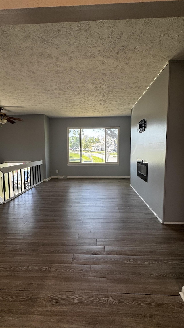 6361 S 140th Ave, Omaha, NE 68137 - unfurnished living room with a textured ceiling, dark wood-style floors, a ceiling fan, and a glass covered fireplace