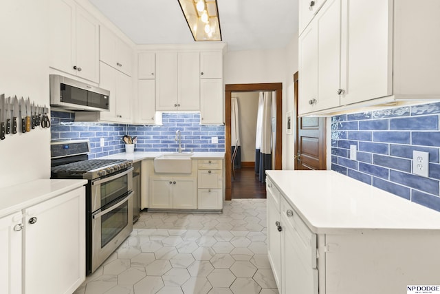 4340 Miami St, Omaha, NE 68104 - kitchen with appliances with stainless steel finishes, light countertops, tasteful backsplash, white cabinetry, and light tile patterned floors