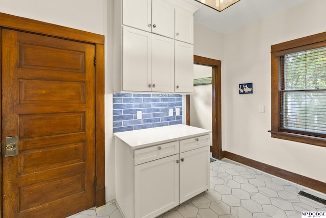 4340 Miami St, Omaha, NE 68104 - kitchen with light countertops, white cabinets, decorative backsplash, and light tile patterned floors