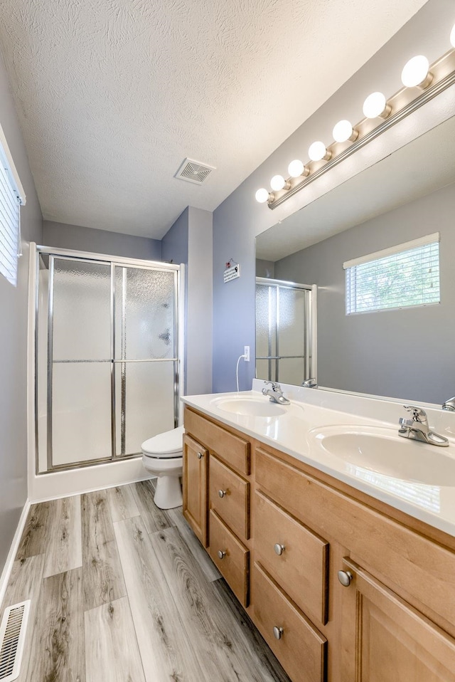 18653 Borman St, Omaha, NE 68135 - full bathroom featuring wood finished floors, a stall shower, double vanity, and a textured ceiling