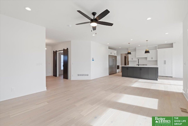 5721 N 197th Ave, Omaha, NE 68022 - unfurnished living room featuring a barn door, light wood-type flooring, recessed lighting, and a ceiling fan
