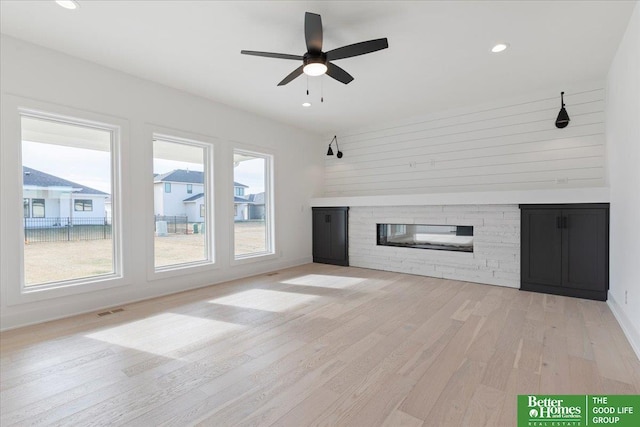 5721 N 197th Ave, Omaha, NE 68022 - unfurnished living room featuring a stone fireplace, light wood finished floors, ceiling fan, and recessed lighting