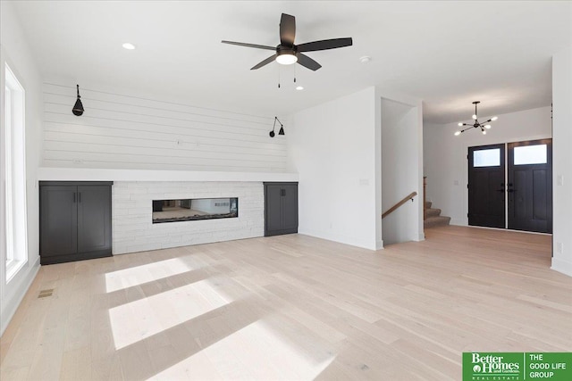 5721 N 197th Ave, Omaha, NE 68022 - unfurnished living room with a glass covered fireplace, stairs, wood finished floors, recessed lighting, and a chandelier