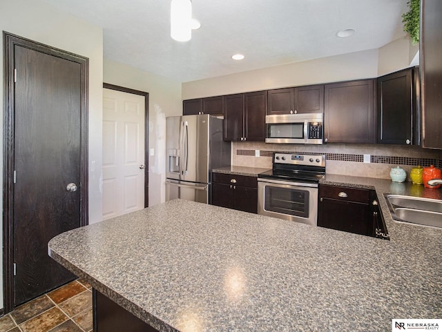 1809 SW Derek Ave, Lincoln, NE 68522 - kitchen with stainless steel appliances, dark brown cabinetry, dark countertops, and decorative backsplash