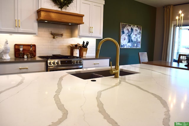 5445 Kestrel Pkwy, Omaha, NE 68022 - kitchen with gas stove, backsplash, custom exhaust hood, white cabinets, and light stone countertops