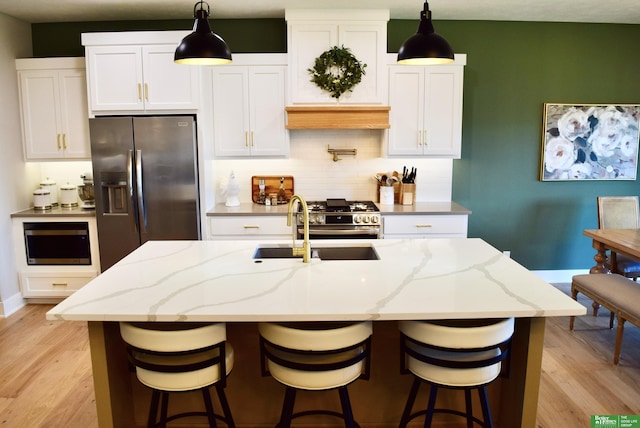 5445 Kestrel Pkwy, Omaha, NE 68022 - kitchen featuring stainless steel appliances, light wood-style flooring, a center island with sink, and white cabinetry
